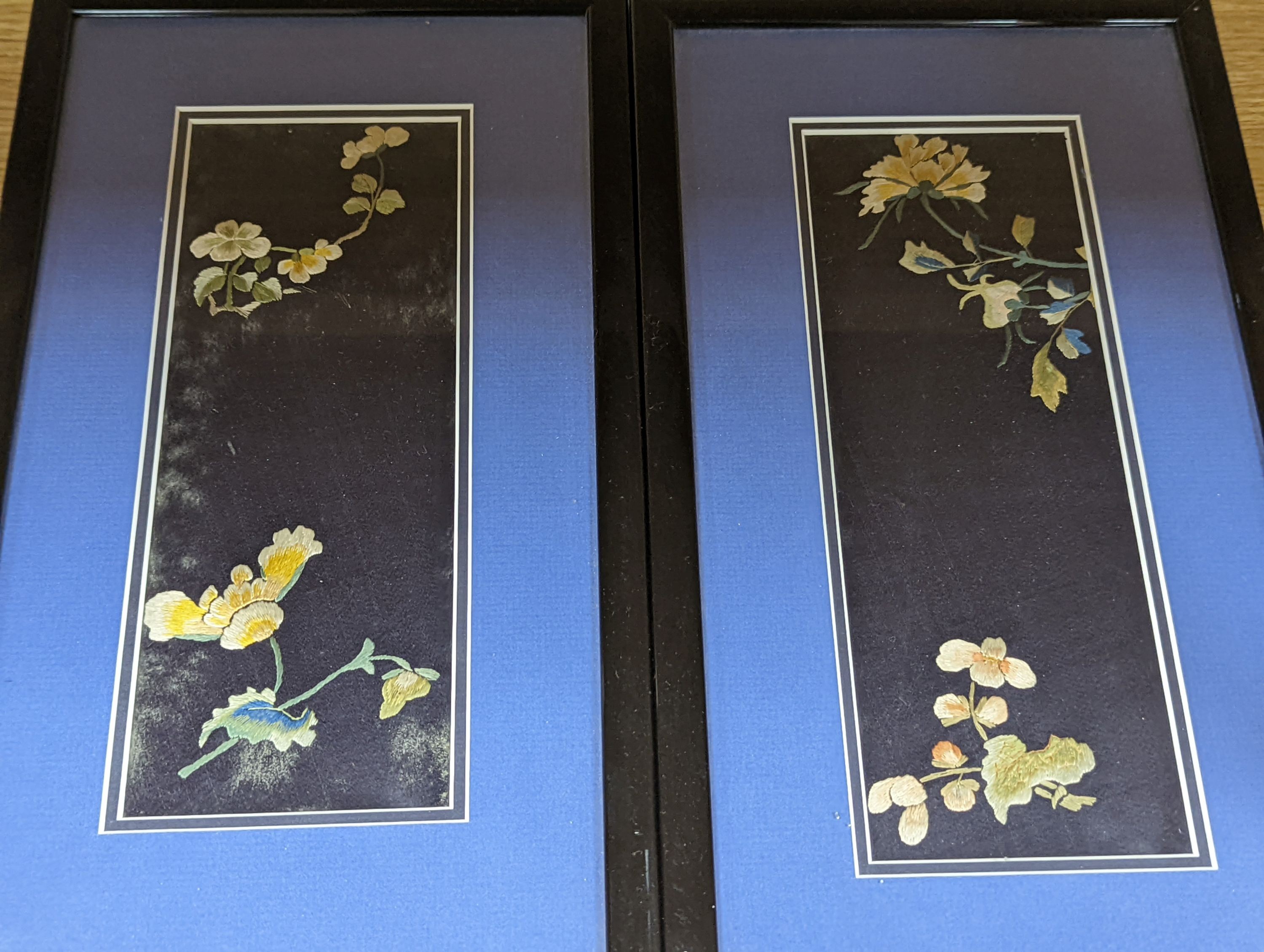 A set of four Chinese silk embroidered motifs, a pair of floral silk motifs and a later pair f sleeve bands, all framed